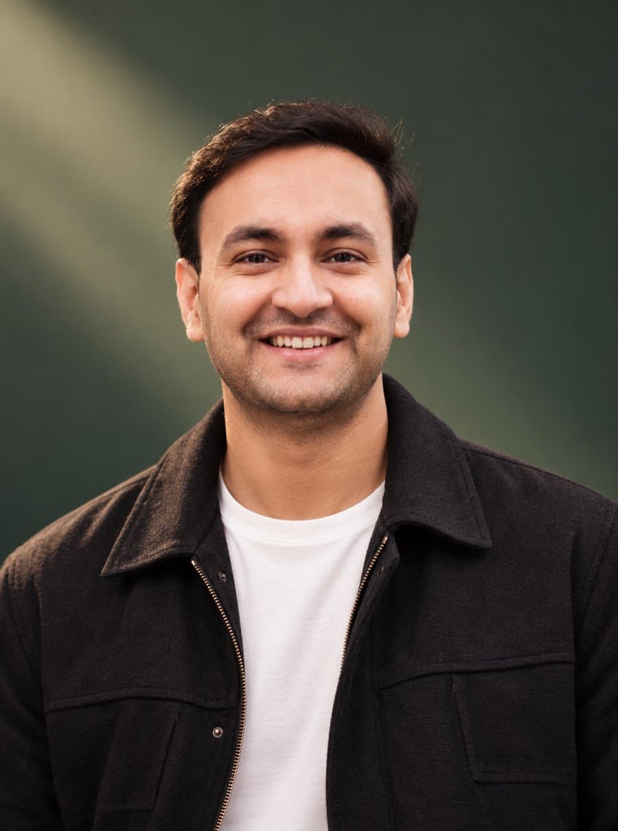 Portrait of Gopal Krishan Sharma, Senior UX Designer, smiling in a dark jacket against a green backdrop
